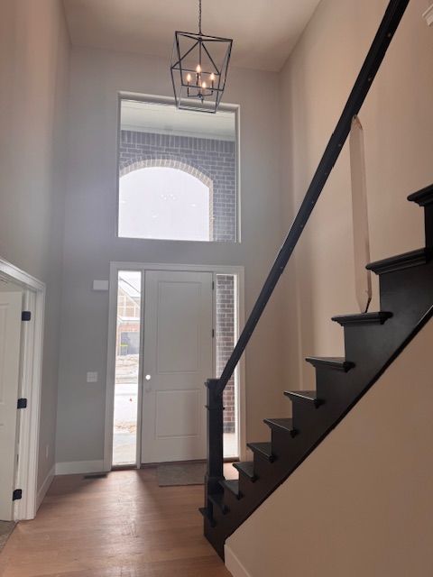 entrance foyer featuring light wood-type flooring, a towering ceiling, baseboards, and stairs