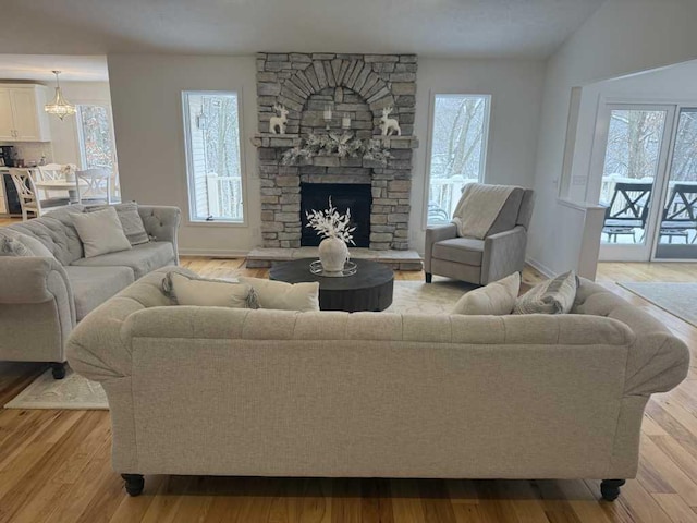 living room with light hardwood / wood-style floors and a stone fireplace