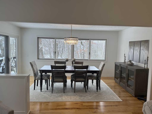 dining area with light wood-type flooring and an inviting chandelier