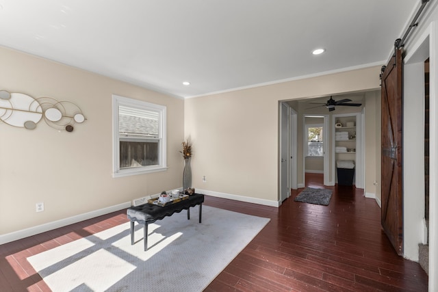 interior space featuring a barn door, ceiling fan, crown molding, and dark hardwood / wood-style floors