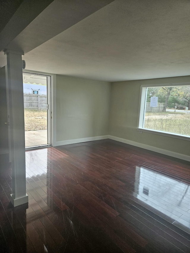 spare room featuring a wealth of natural light and dark wood-type flooring