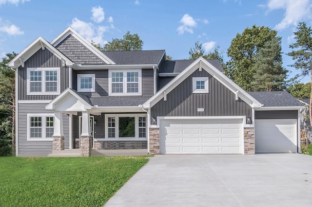 craftsman house with stone siding, board and batten siding, a front yard, and a garage