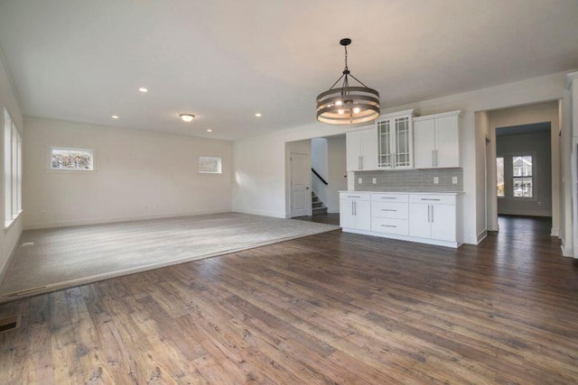 interior space with dark wood-type flooring, recessed lighting, an inviting chandelier, baseboards, and stairs