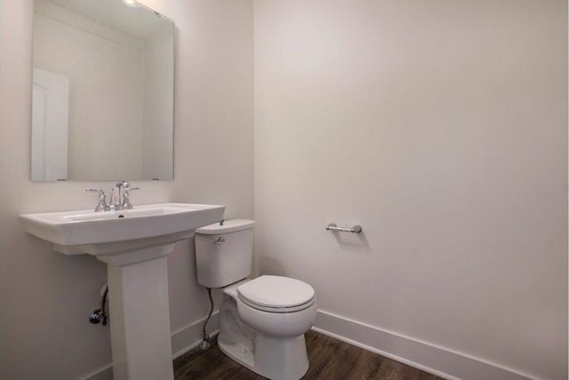 bathroom featuring toilet, wood finished floors, and baseboards