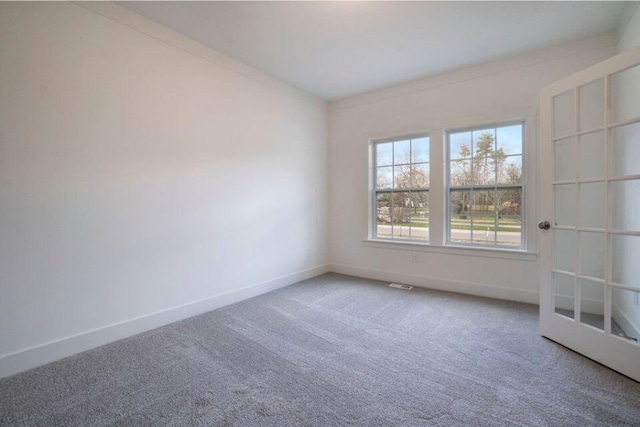 carpeted spare room with visible vents and baseboards