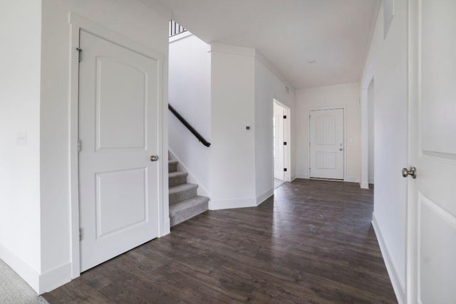 corridor with stairway, wood finished floors, and baseboards