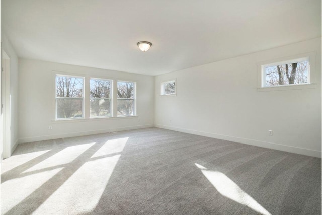 unfurnished room featuring baseboards, carpet floors, and plenty of natural light