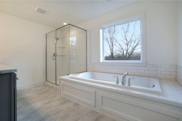 bathroom featuring visible vents, a garden tub, wood finished floors, a shower stall, and baseboards