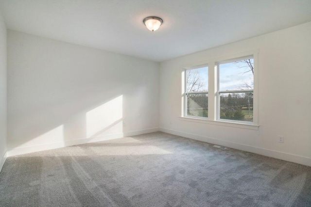 spare room featuring carpet and baseboards