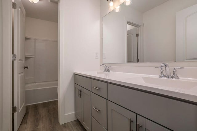 full bath with double vanity, wood finished floors, and a sink