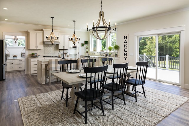 dining space with a notable chandelier, plenty of natural light, dark wood-style flooring, and ornamental molding