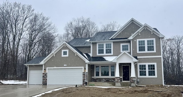 craftsman-style home featuring stone siding, driveway, and an attached garage