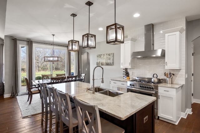 kitchen featuring pendant lighting, white cabinets, high end range, and wall chimney exhaust hood