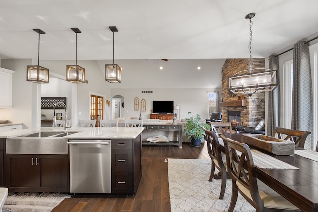 kitchen with a stone fireplace, dishwasher, hanging light fixtures, sink, and dark hardwood / wood-style floors