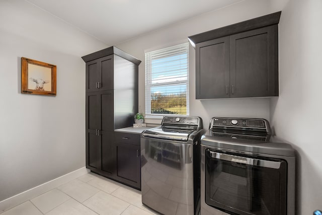 laundry room featuring cabinets, light tile patterned floors, and separate washer and dryer