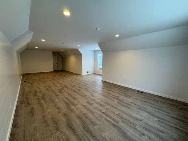 additional living space with vaulted ceiling and wood-type flooring