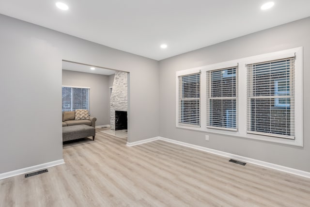 living room with a stone fireplace and light hardwood / wood-style flooring