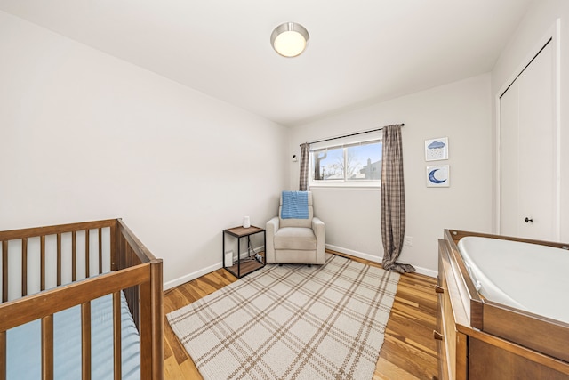 bedroom with a nursery area and light wood-type flooring