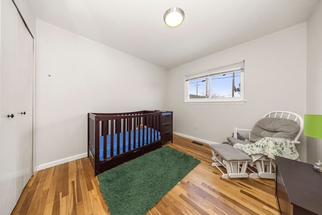 bedroom featuring a closet, a nursery area, and hardwood / wood-style flooring