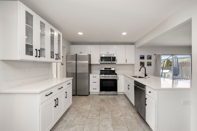 kitchen featuring kitchen peninsula, sink, white cabinets, and stainless steel appliances