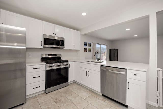 kitchen featuring kitchen peninsula, appliances with stainless steel finishes, white cabinets, and sink