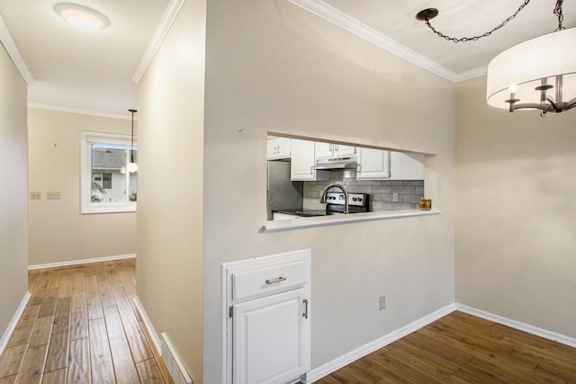 hall with hardwood / wood-style floors, an inviting chandelier, and crown molding