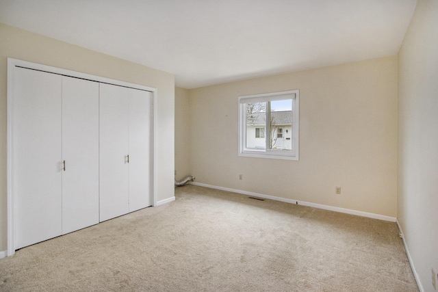 unfurnished bedroom with light colored carpet and a closet