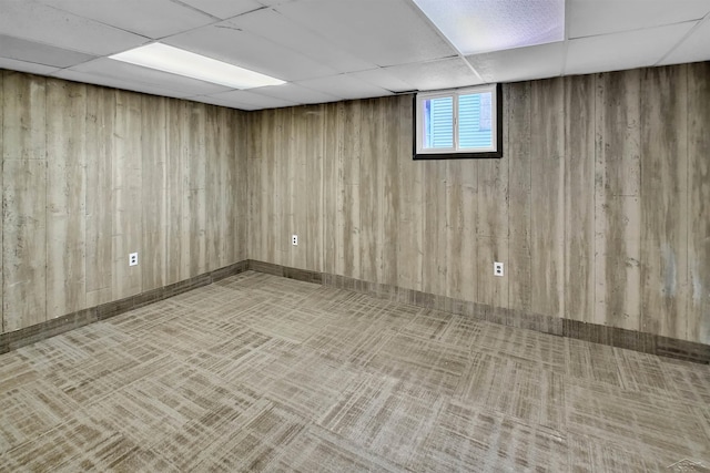 basement with a paneled ceiling, carpet flooring, and wooden walls