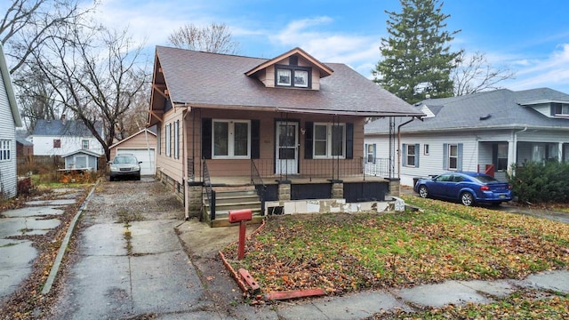 bungalow-style house with covered porch, a garage, and an outdoor structure