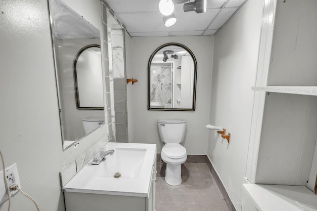 bathroom featuring tile patterned flooring, vanity, a paneled ceiling, and toilet