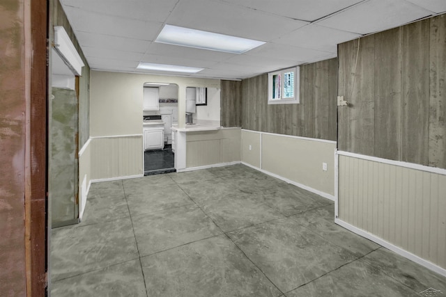 interior space featuring a drop ceiling and wood walls