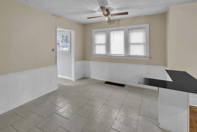 empty room with a paneled ceiling, ceiling fan, and light tile patterned floors