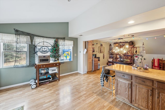 kitchen with light wood-type flooring, vaulted ceiling, and a notable chandelier