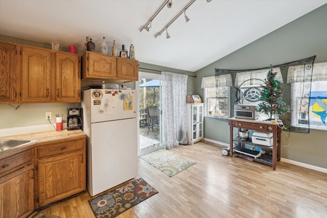 kitchen featuring sink, light wood-type flooring, lofted ceiling, and white refrigerator