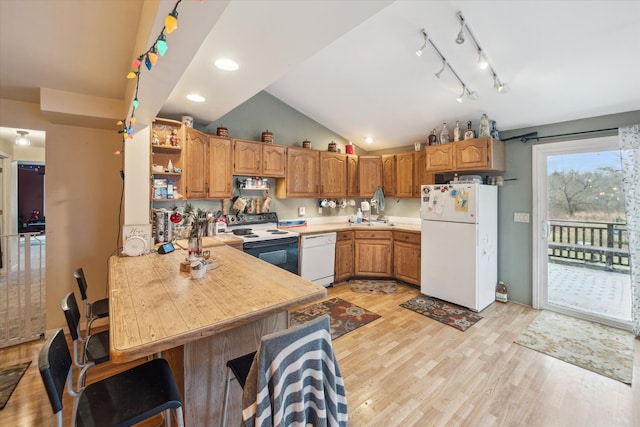 kitchen with kitchen peninsula, white appliances, vaulted ceiling, sink, and light hardwood / wood-style flooring