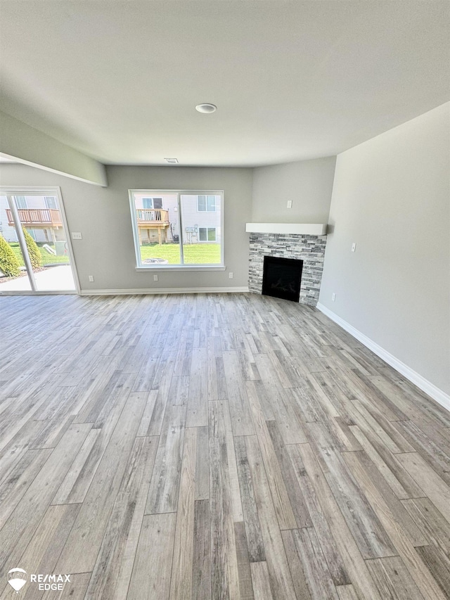 31007 Gregory St, Grand Blanc, MI 48439 - unfurnished living room featuring baseboards, plenty of natural light, wood finished floors, and a stone fireplace