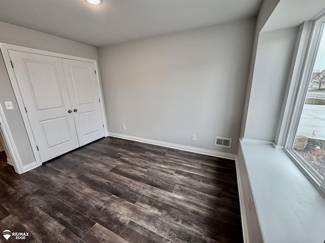 unfurnished bedroom featuring dark hardwood / wood-style floors and a closet