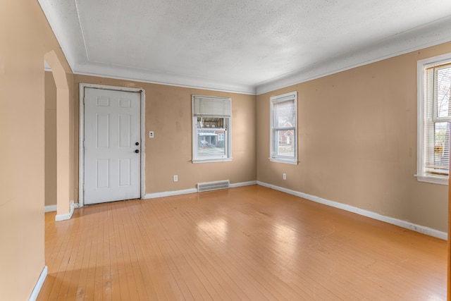 interior space featuring a textured ceiling, light hardwood / wood-style flooring, and ornamental molding