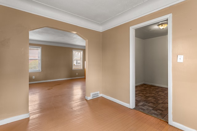 spare room featuring light hardwood / wood-style floors, ornamental molding, and a textured ceiling