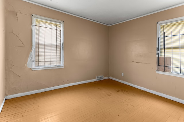 empty room featuring light wood-type flooring and crown molding