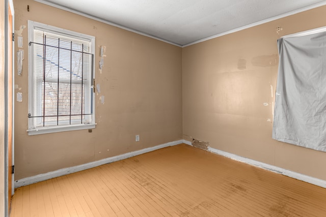 unfurnished room featuring a healthy amount of sunlight, wood-type flooring, and ornamental molding