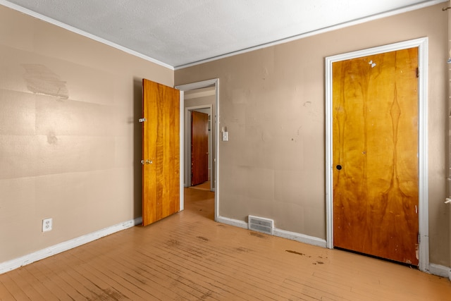 unfurnished bedroom featuring ornamental molding, a textured ceiling, and light hardwood / wood-style flooring