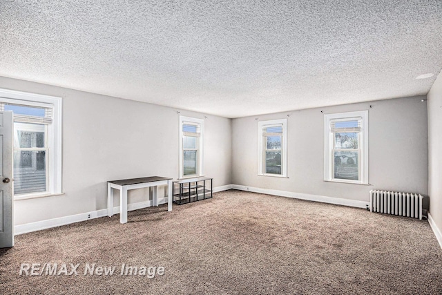 spare room featuring carpet, radiator heating unit, and a textured ceiling