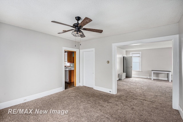 unfurnished room with dark colored carpet, radiator heating unit, and a textured ceiling