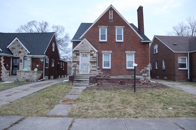 view of front facade featuring a front yard, a chimney, and brick siding