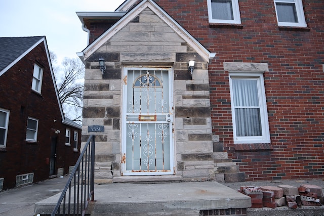 entrance to property featuring stone siding and brick siding