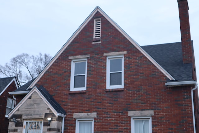 view of home's exterior with a chimney and brick siding