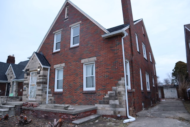 view of side of property featuring brick siding and a chimney