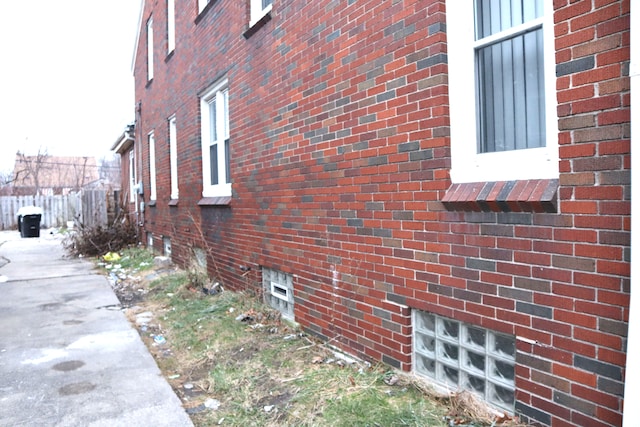 view of property exterior featuring fence and brick siding