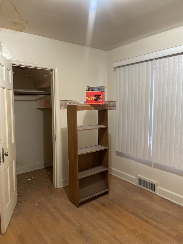 unfurnished bedroom with wood finished floors and visible vents